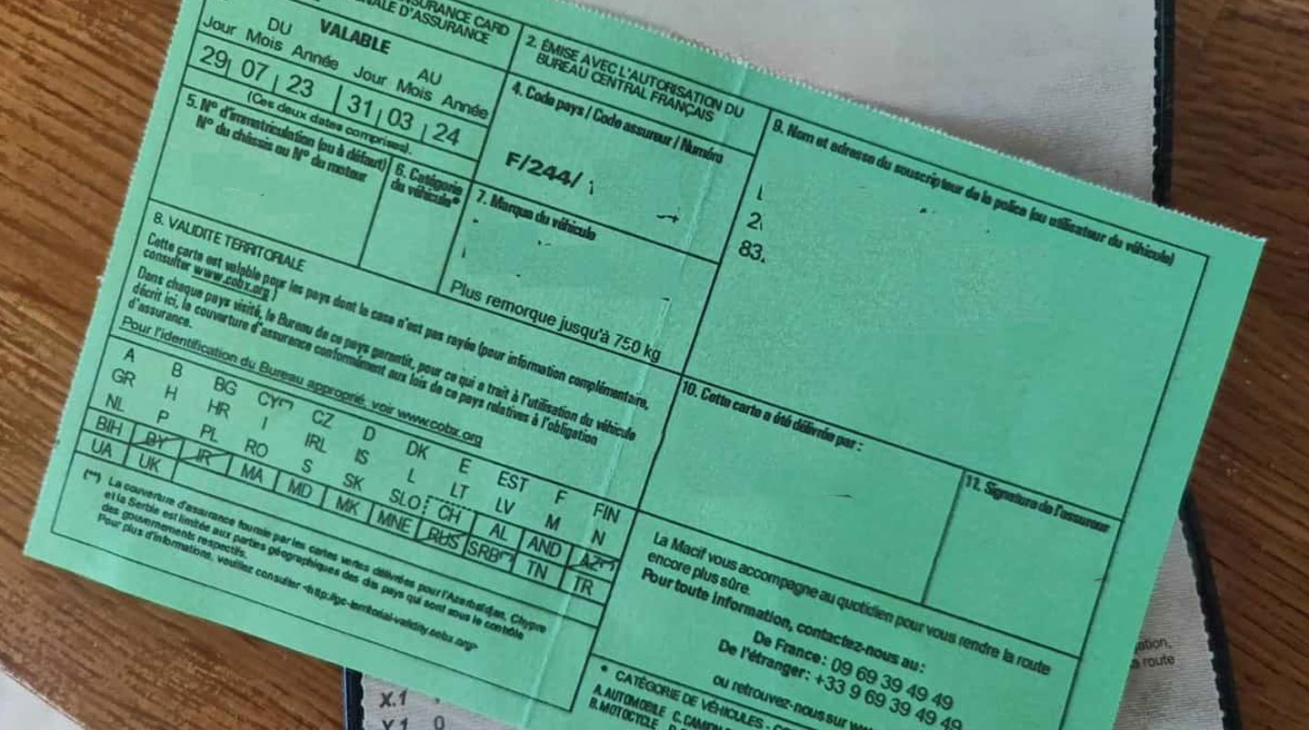 Gros plan sur une carte verte d'assurance et des clés de 4x4 posées sur un tableau de bord moderne