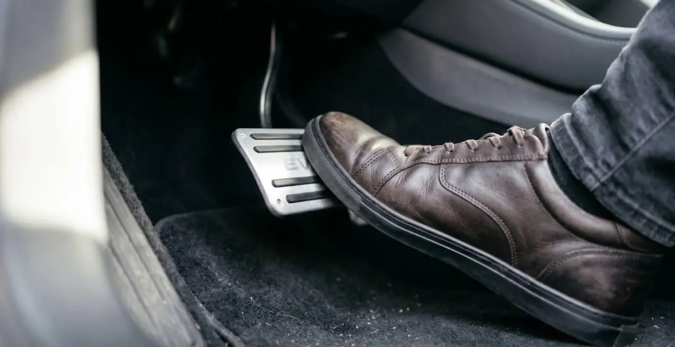 Gros plan sur un pied dosant délicatement la pédale d'accélérateur d'une voiture électrique avec indicateur de mode Eco visible