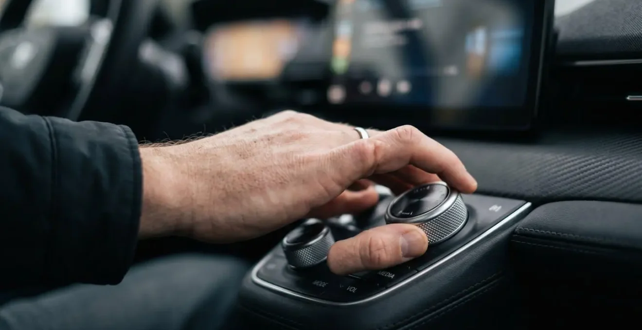 Main d'un conducteur ajustant les paramètres sur une interface de planification de trajet avancée sur l'écran d'un véhicule.