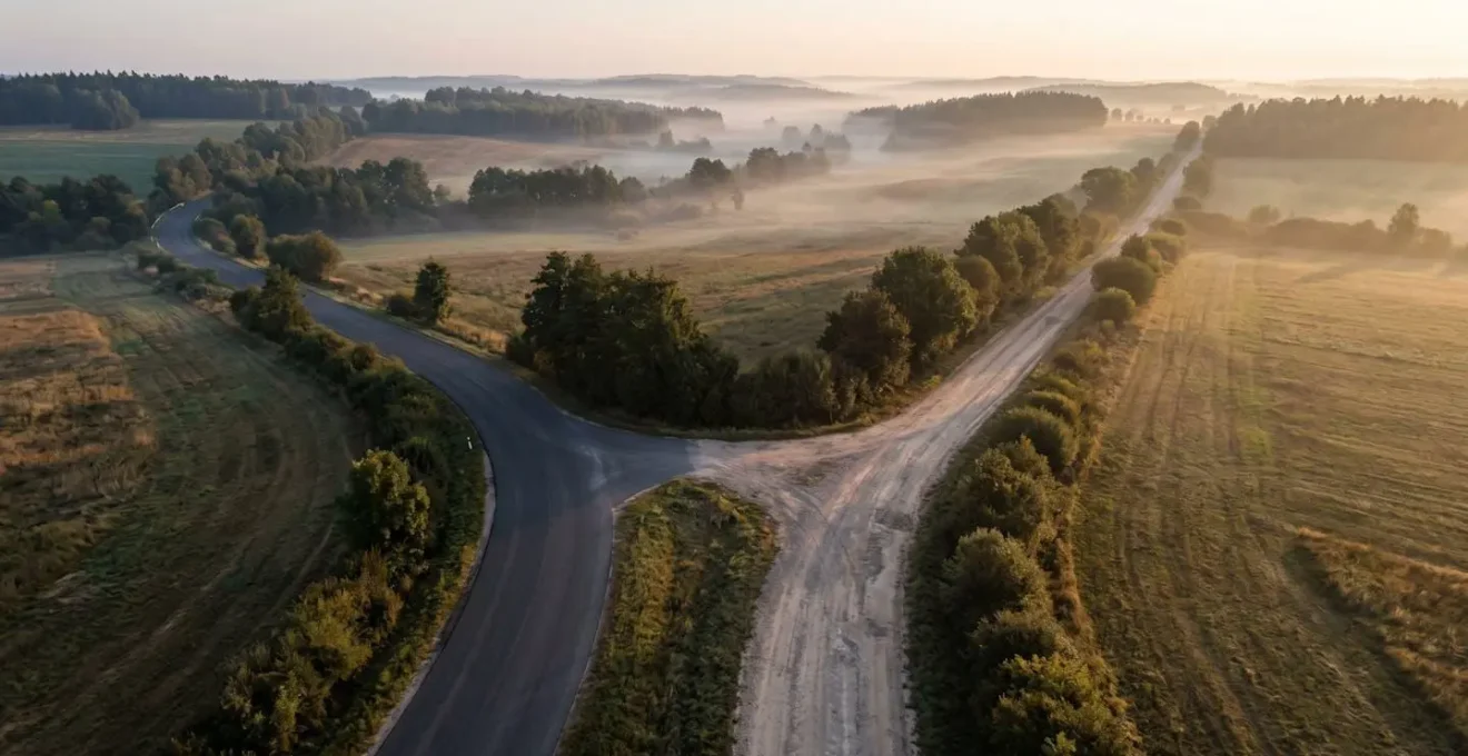 Vue aérienne d'une intersection entre route goudronnée et chemin de terre en zone rurale